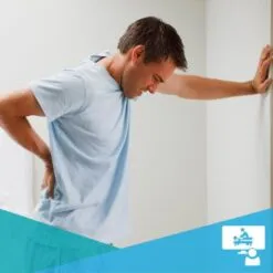Young man with lower back pain leaning against a wall