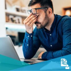 Man with migraine headache working on a laptop