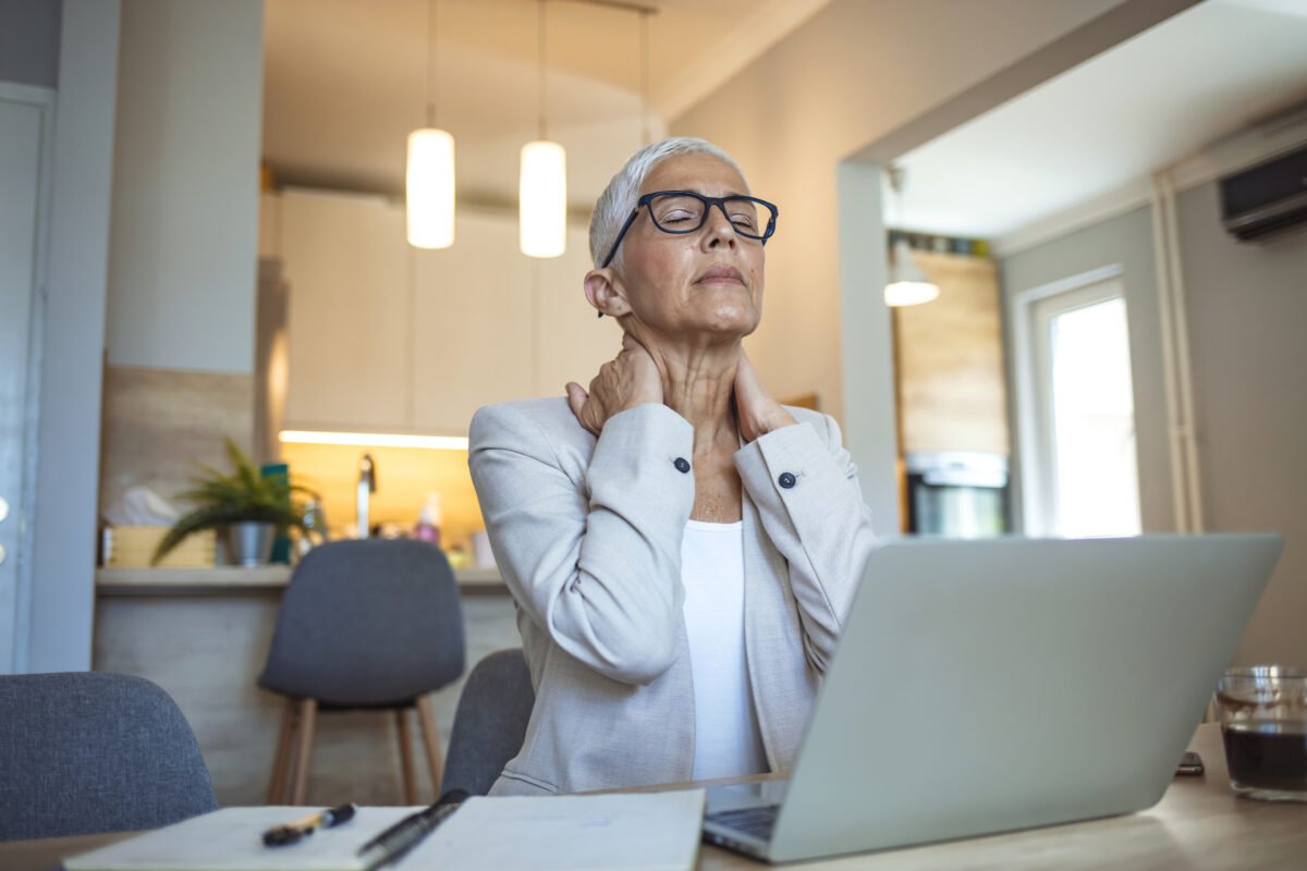 Mature woman with myofascial pain syndrome massaging her neck with both hands