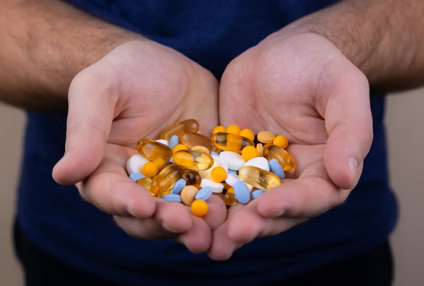Two hands holding many pills