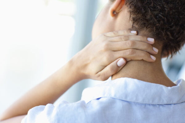 Woman with neck pain touching her neck