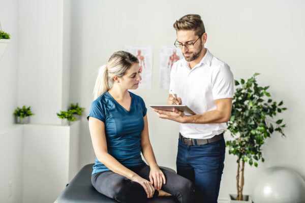 Male chiropractor receiving a history from a young female patient