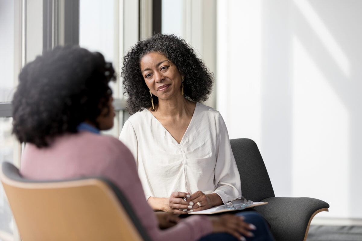 Mature female clinician sitting listening to a patient