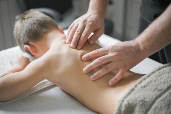 Chiropractor palpates young patient's middle back