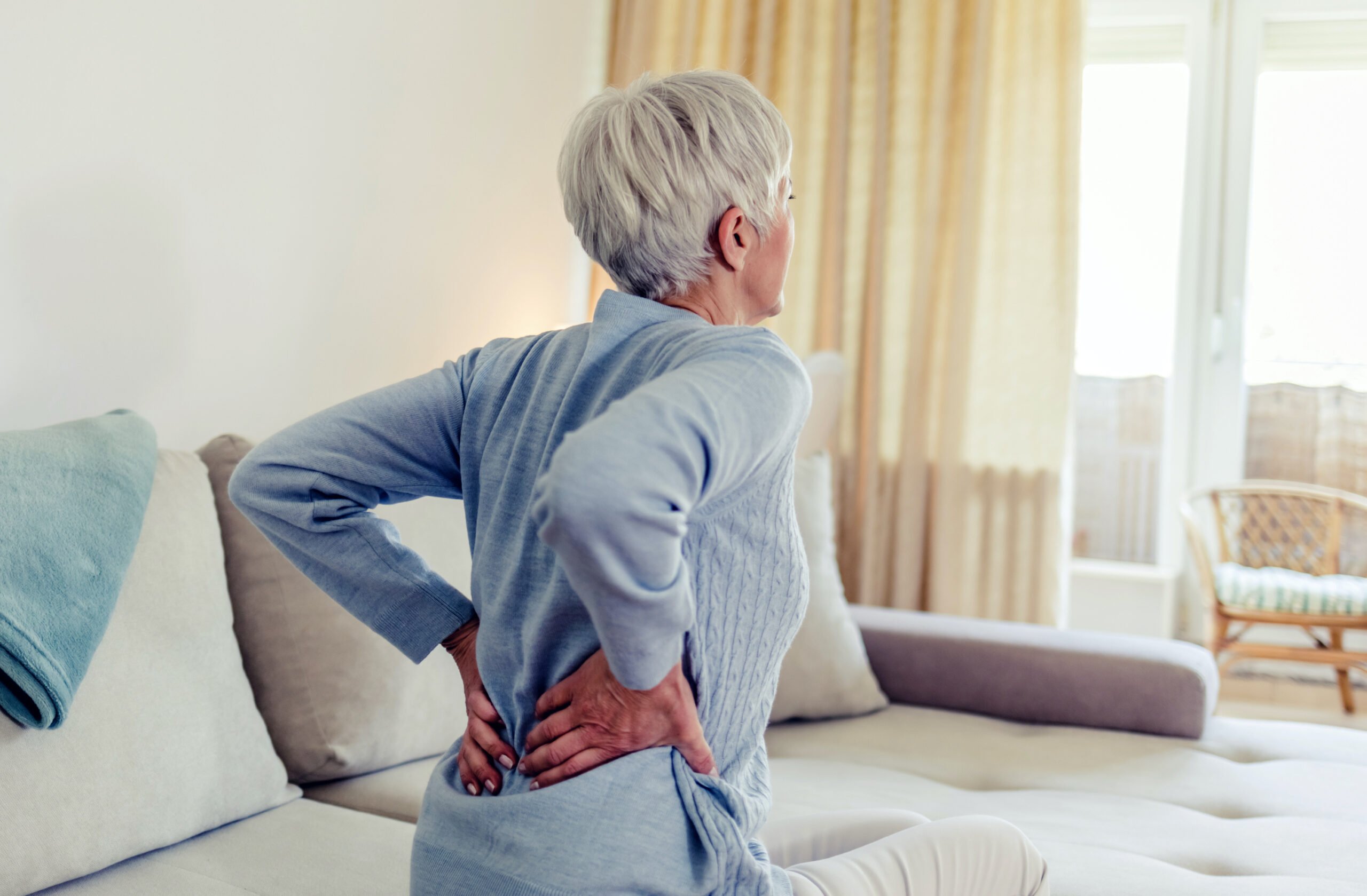 Elderly woman feels back pain, massaging aching muscles