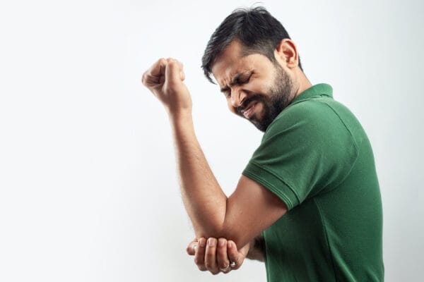 Man with painful grimace expression holding his elbow joint