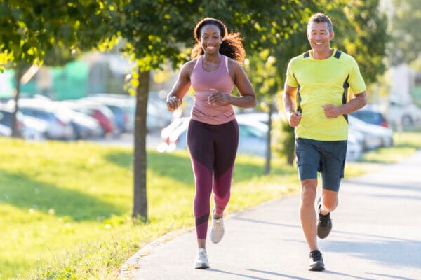 Smiling man and woman running in a public park.