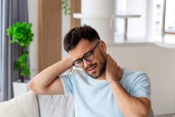 Unhappy young man suffering from pain in the neck