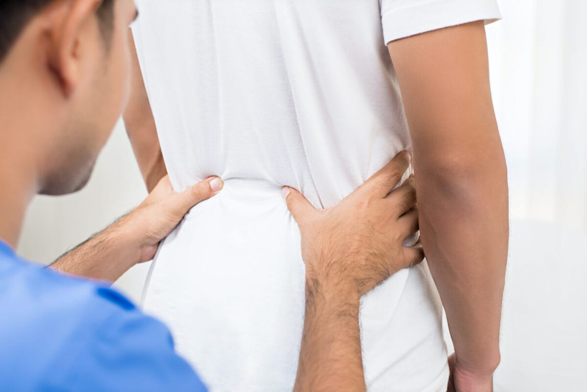Male chiropractor assessing a patient's sacroiliac joint pain