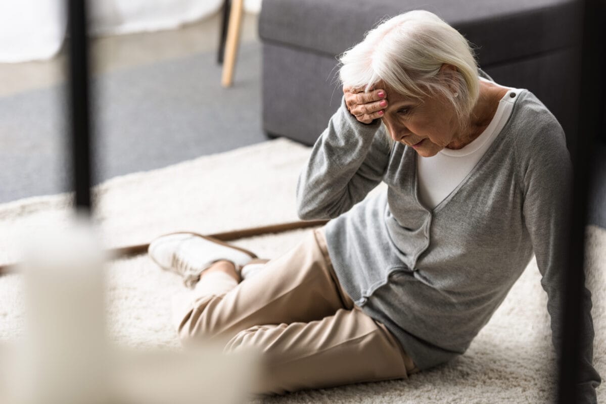 Older woman holding her head after falling on the floor