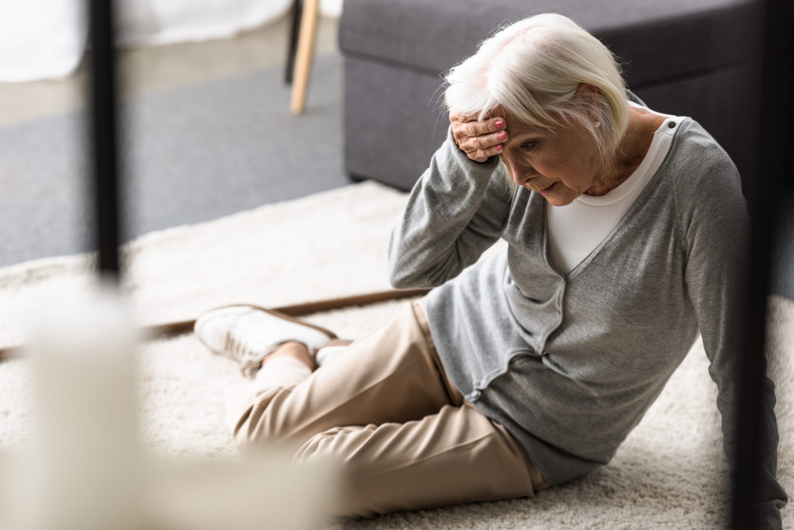 Older woman holding her head after falling on the floor
