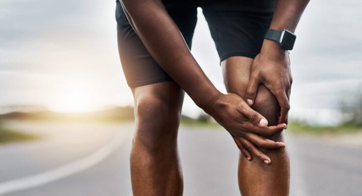 Hands grasping a sore knee