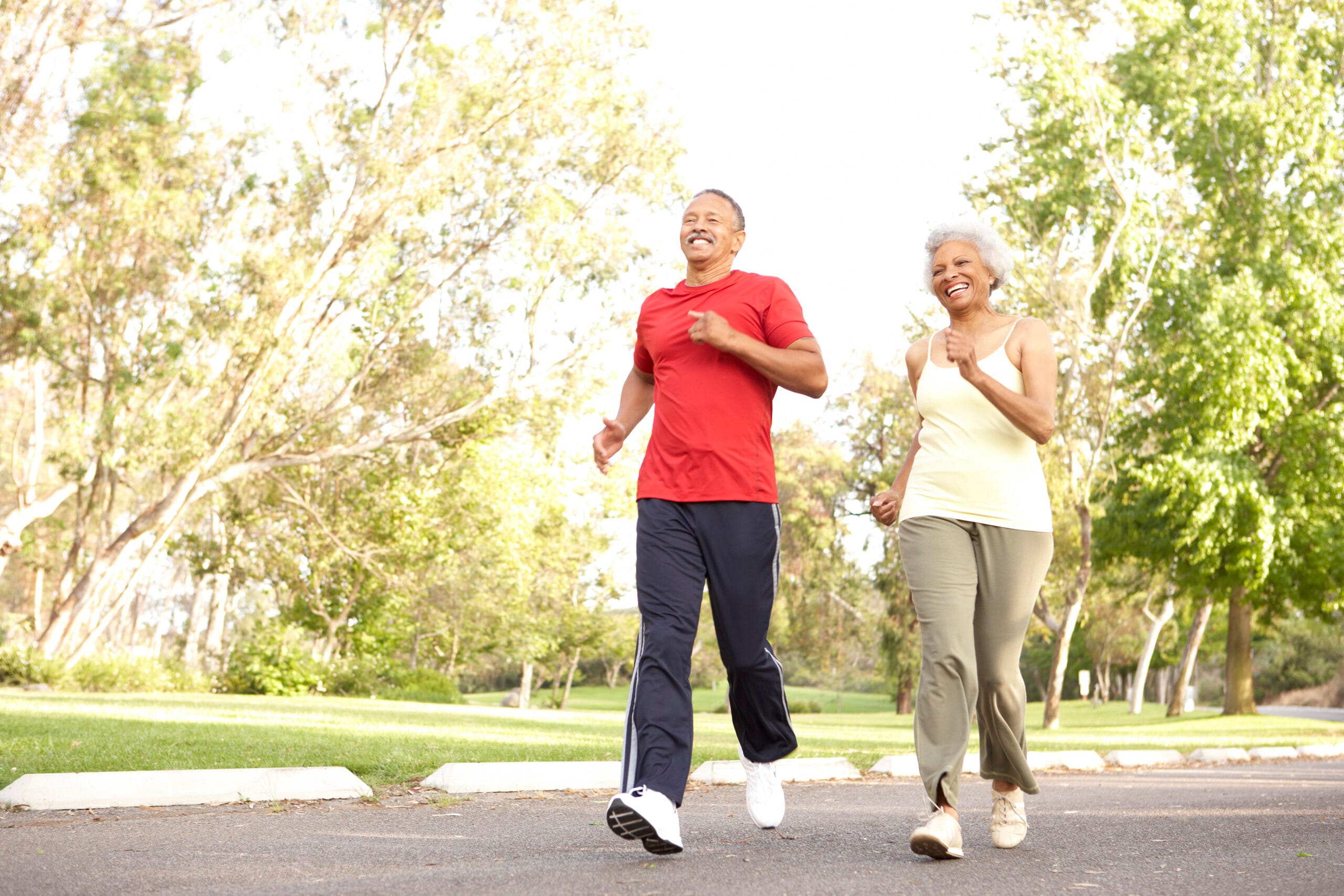Senior Couple Jogging In Park Smiling