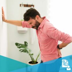 Young man leaning against a wall and wincing due to low back pain