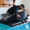 Young male chiropractor adjusting a patient's low back in a side posture position