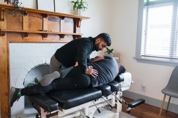 Young male chiropractor adjusting a patient's low back in a side posture position