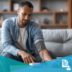 Young black man sitting on couch and checking blood pressure with a home measurement device