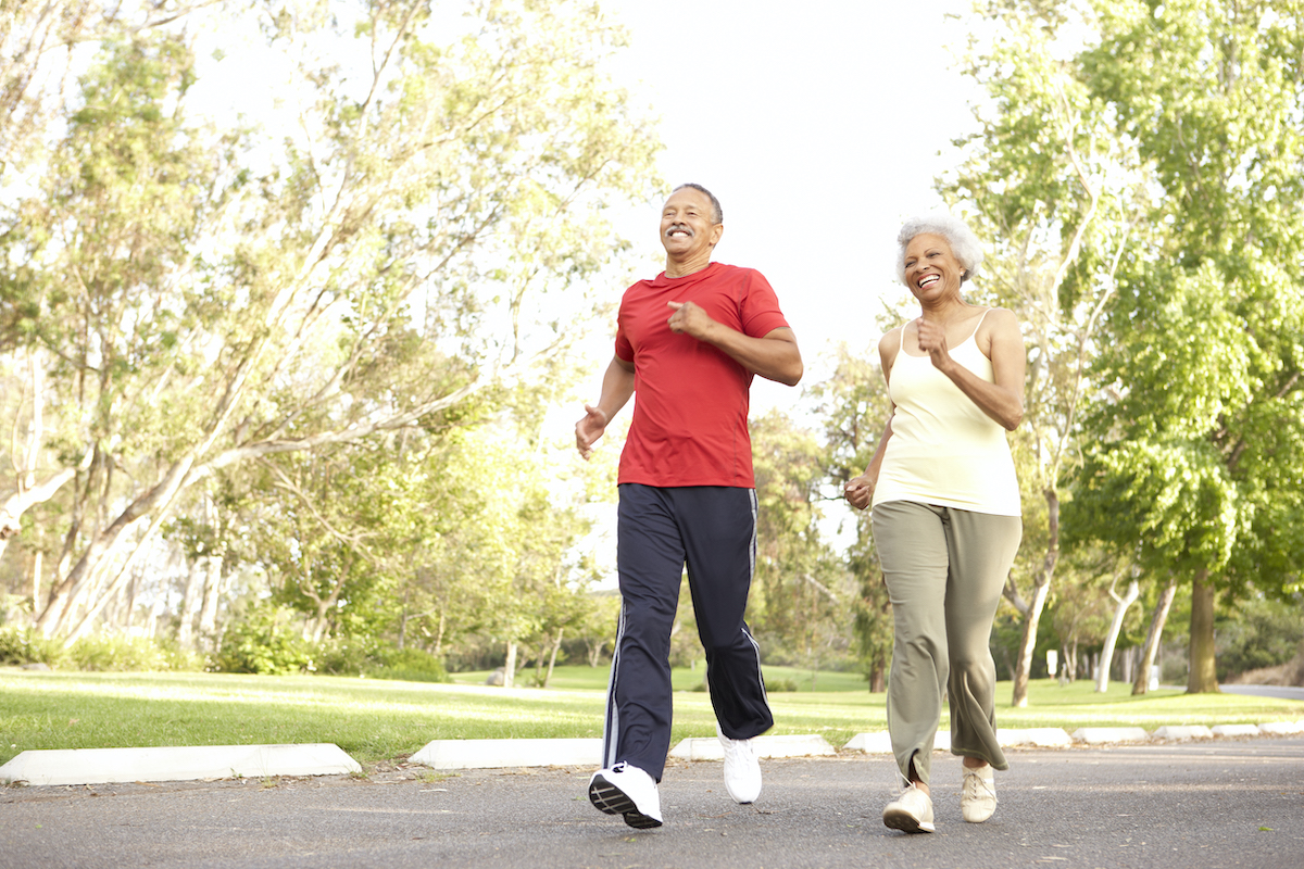 Senior couple jogging in a park smiling